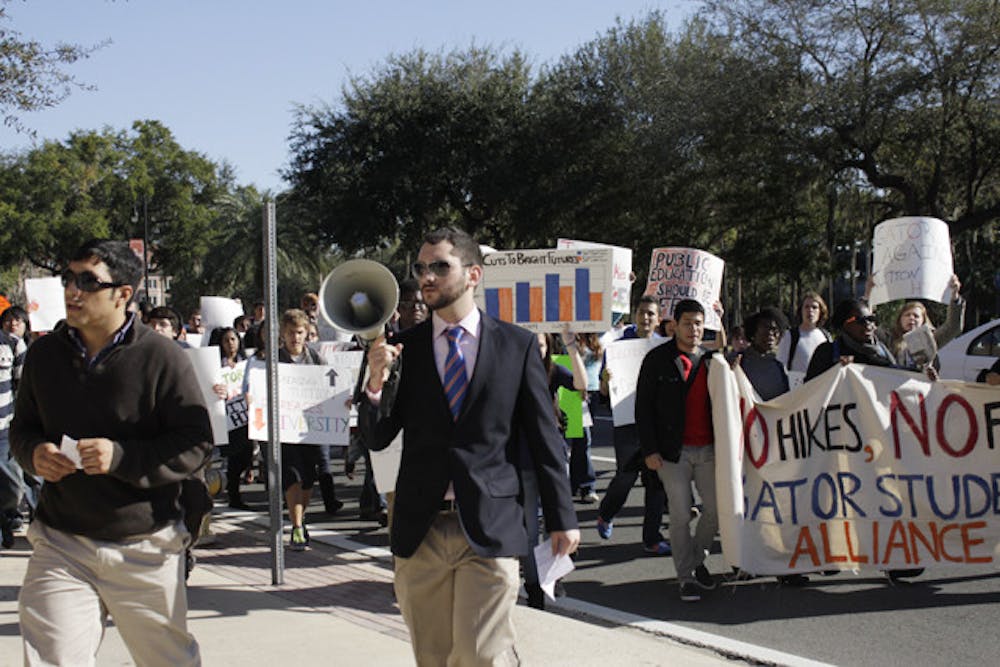 <p>Jose Soto, a fourth-year Ph.D. candidate in food and resource economics, 31, left, and anthropology junior Robbey Hayes, 22, right, lead a group of about 60 protesters to Emerson Alumni Hall, where the UF Board of Trustees met Thursday. They rallied against tuition and fees increases.</p>