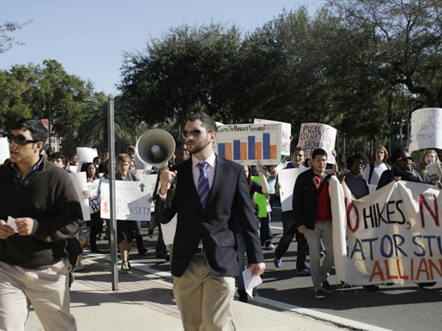 Jose Soto, a fourth-year Ph.D. candidate in food and resource economics, 31, left, and anthropology junior Robbey Hayes, 22, right, lead a group of about 60 protesters to Emerson Alumni Hall, where the UF Board of Trustees met Thursday. They rallied against tuition and fees increases.