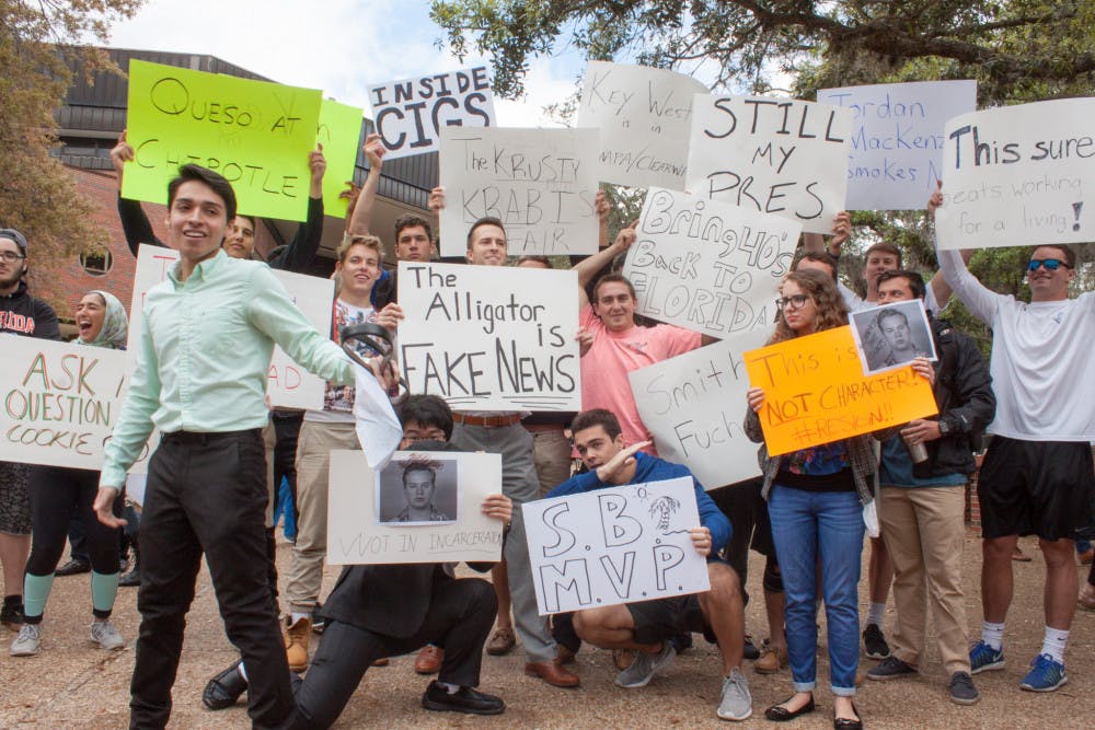 Anthony Rojas (front), a 21-year-old third-year political science major who organized the protest against student body president Smith Myers, tries to speak to a crowd while counter-protesters hold signs behind him and other protesters. 