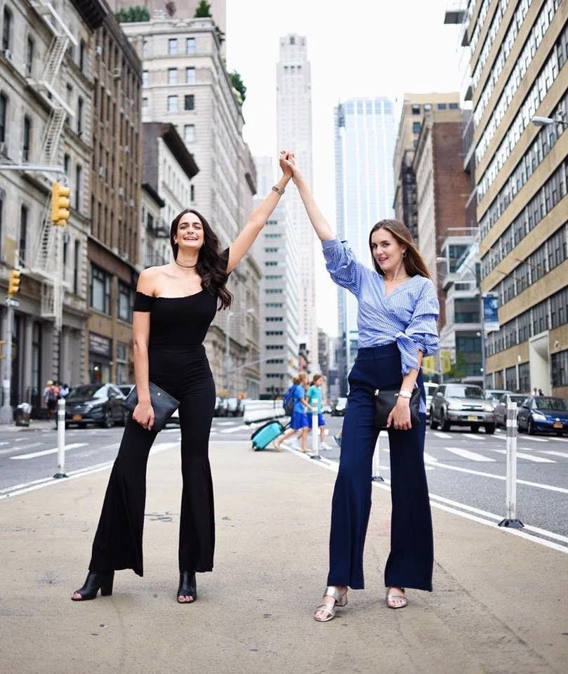 Shir Ibgui, left, and Jamie Wilkinson, right, hold hands in the streets of New York City. The pair talks about their travels, food recommendations and wellness tips on their lifestyle blog, "NOTURAVG."