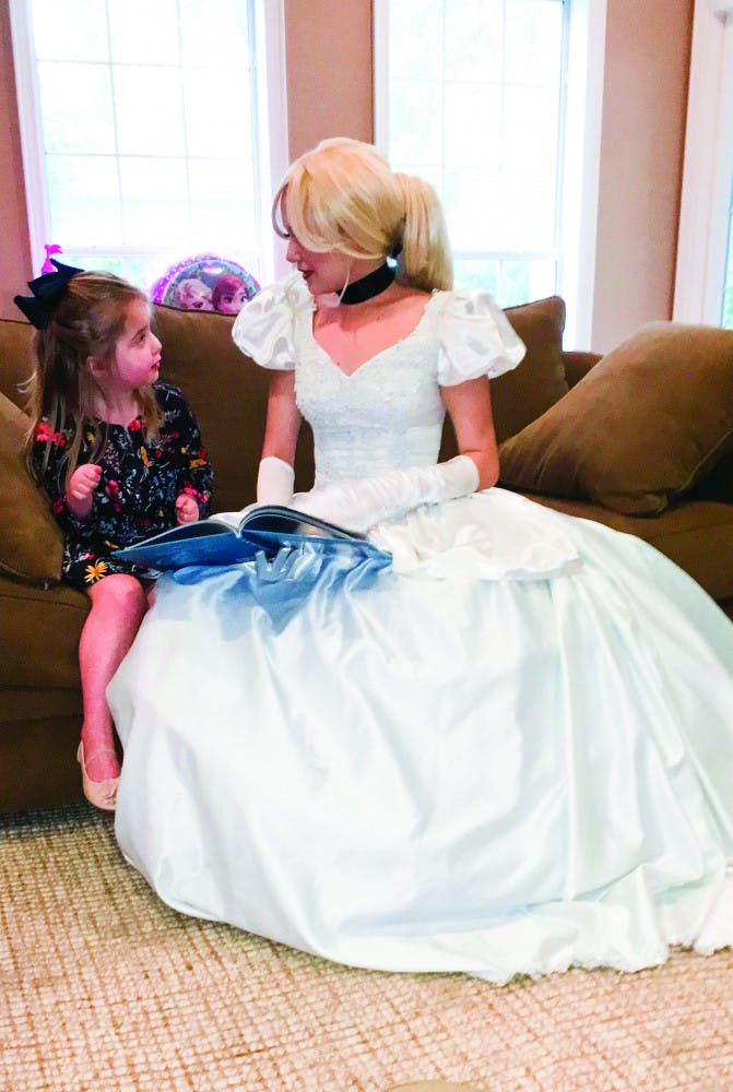 Dressed as Cinderella, Kailyn Allen, a 22-year-old UF law student, reads a book to 4-year-old Phoebe Dooley. Dooley was diagnosed with a terminal brain tumor in March 2016. 