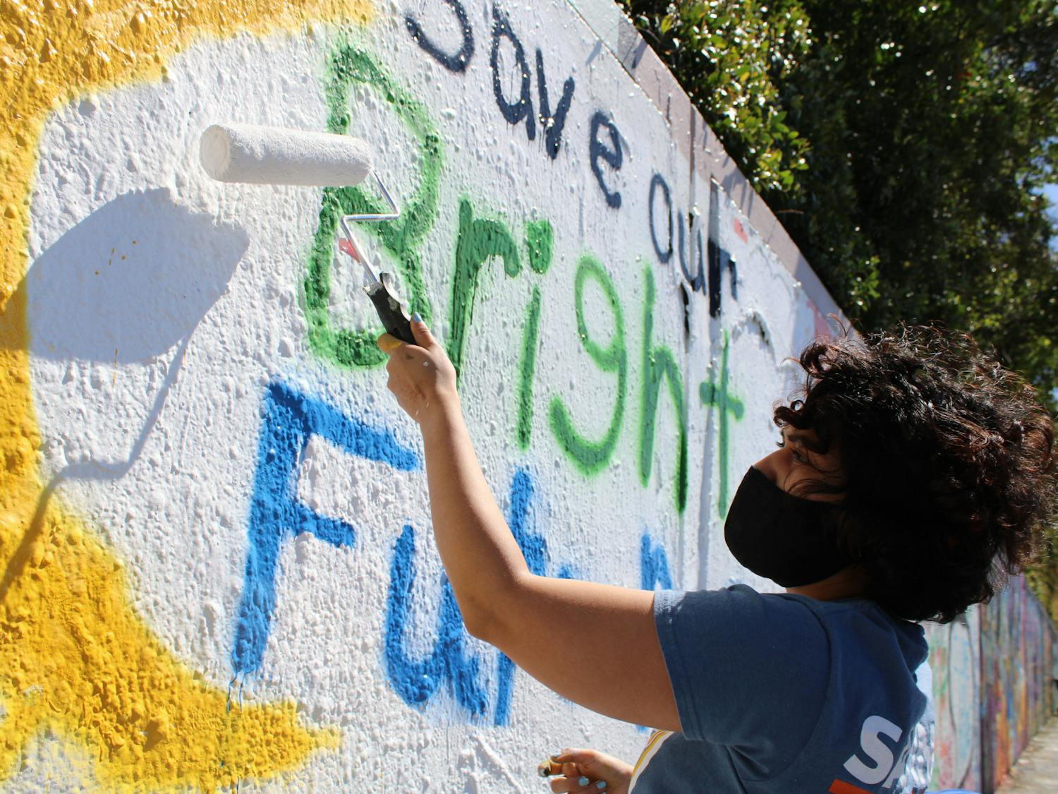 Alondra Arce, 20, a UF sustainability sophomore, paints a mural that says &quot;Save Our Bright Futures&quot; on Sunday, March 7, 2021. Arce recruited student volunteers to help her create the mural along 34th Street in Gainesville to raise awareness about Senate Bill 86, which would limit some students&#x27; access to state funding for college if passed.