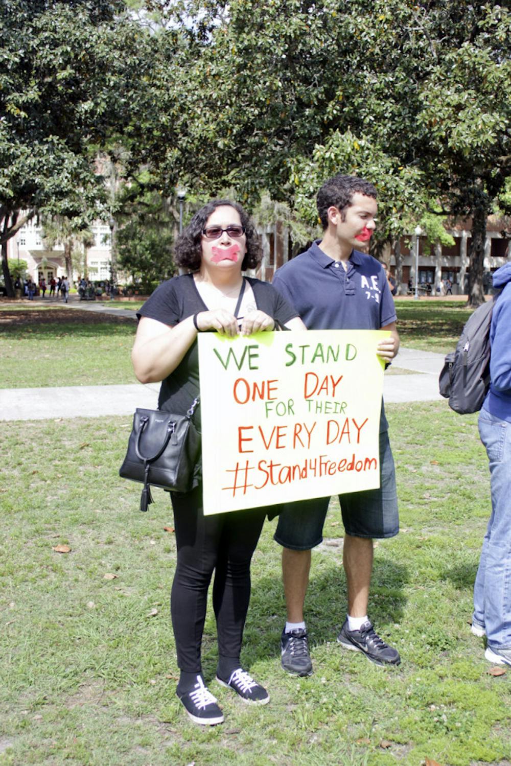 <p>Trish Kearney, a 43-year-old UF health education and behavior junior, and Jonathan Batista, a 23-year-old UF chemical engineering senior, stand on Plaza of the Americas on Tuesday. They and four other students marched between there and Turlington Plaza with their mouths taped and hands tied to highlight human trafficking.</p>