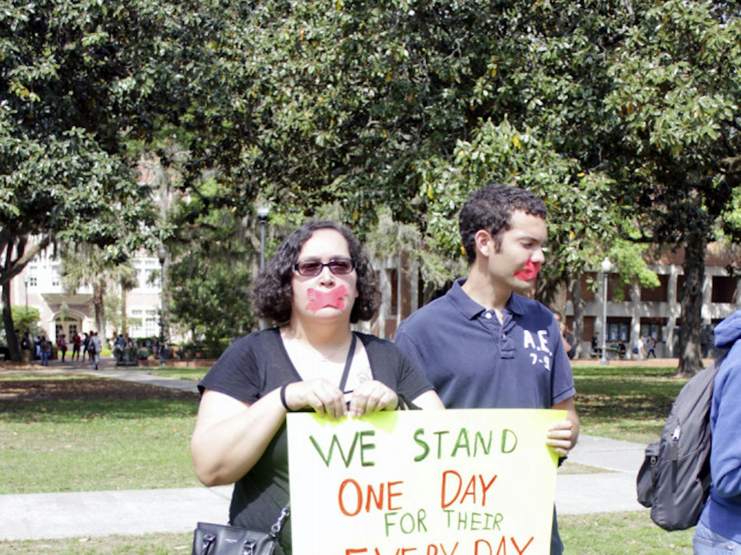 Trish Kearney, a 43-year-old UF health education and behavior junior, and Jonathan Batista, a 23-year-old UF chemical engineering senior, stand on Plaza of the Americas on Tuesday. They and four other students marched between there and Turlington Plaza with their mouths taped and hands tied to highlight human trafficking.