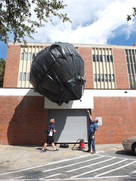 Brad Smith, 57, helps UF junior sculpture student JT Smalley, 36, control a balloon made out of trash bags outside of Fine Arts Building C Thursday morning. The project, designed and created by Smalley for a sculpture assignment, is powered entirely by heat and air.