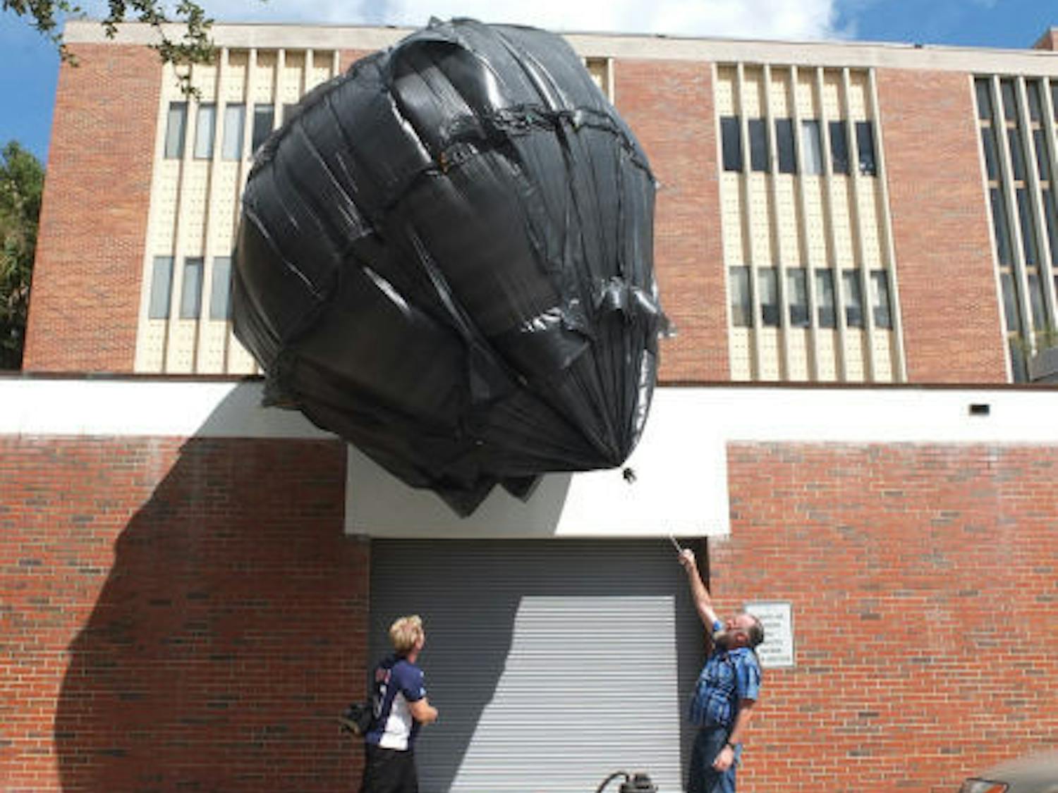 Brad Smith, 57, helps UF junior sculpture student JT Smalley, 36, control a balloon made out of trash bags outside of Fine Arts Building C Thursday morning. The project, designed and created by Smalley for a sculpture assignment, is powered entirely by heat and air.