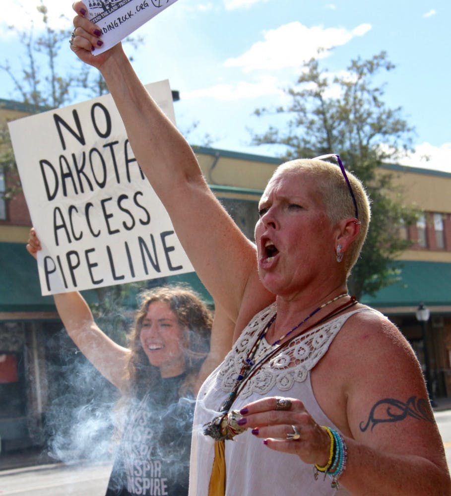 Burning sage, which is sacred to Native Americans, on the corner of University Avenue and Main Street, Marci Munden chants for clean water for the Dakota people. "This is sacred work," Munden, 53, said of protesting the proposed oil pipeline in North Dakota. 