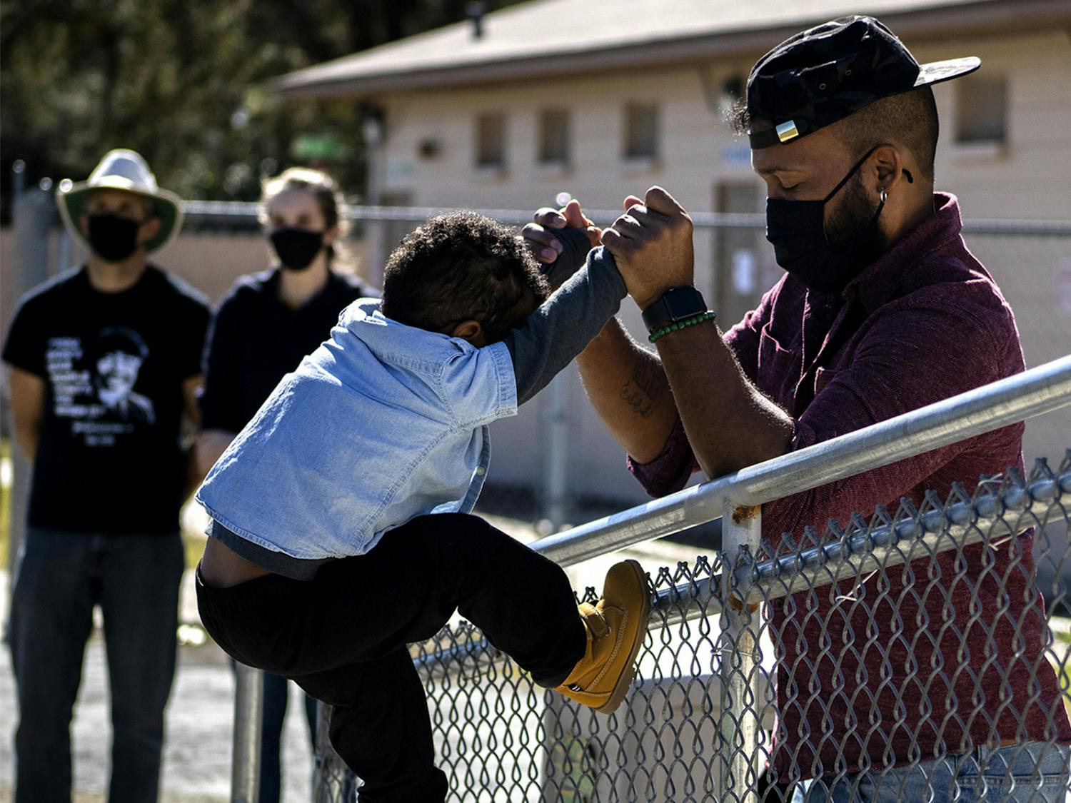 Ryan Hope Travis helps his 2-year-old son, Rezen Hope Travis, climb a fence at the King Celebration at Citizens Field on Monday, Jan. 18, 2021. Ryan Hope Travis said it was the first Martin Luther King Jr. Day celebration Rezen was old enough to understand. “Him knowing his history is the foundation of him being able to grow,” he said.