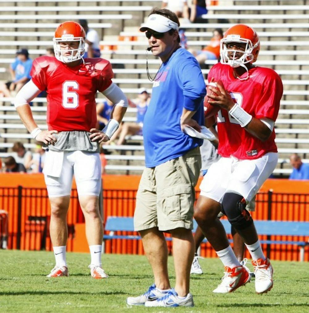 <p>Coach Will Muschamp watches over practice while quarterback Jacoby Brissett (12) &nbsp; passes the ball and Jeff Driskel (6) waits his turn.</p>