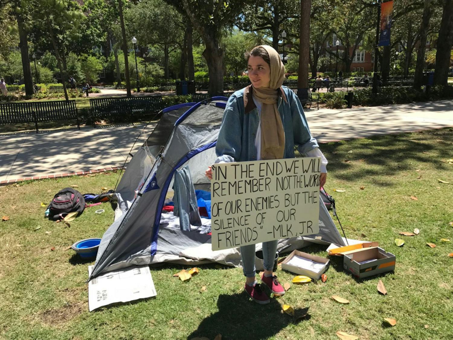Sophia Timm, a 21-year-old UF biology and anthropology senior and the Students Organize for Syria’s chair for the Books Not Bombs campaign, holds up a sign outside the mock-refugee tent. Students Organize for Syria say the display simulates the living conditions of refugees fleeing the Syrian Civil War.