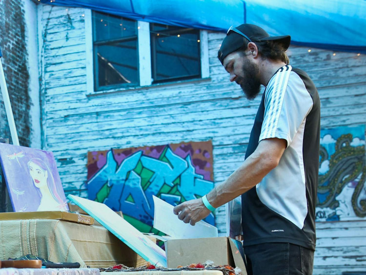Mike Purcell, 38, looks through custom paintings from Zipporah Sky Art during Spirit Fest at The Jam on Sunday.