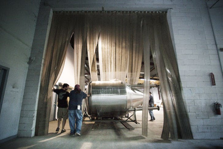 John Denny, 45,&nbsp; the founder of First Magnitude Brewing Company, chats with Randy Coleman, 50, as he and Wells The Losen, 43, guide a 30-barrel fermentation tank into the future brewing room at 1220 SE Veitch St. Thirty barrels of beer is about 930 gallons. The owners said they plan to be open for business by late July.
&nbsp;