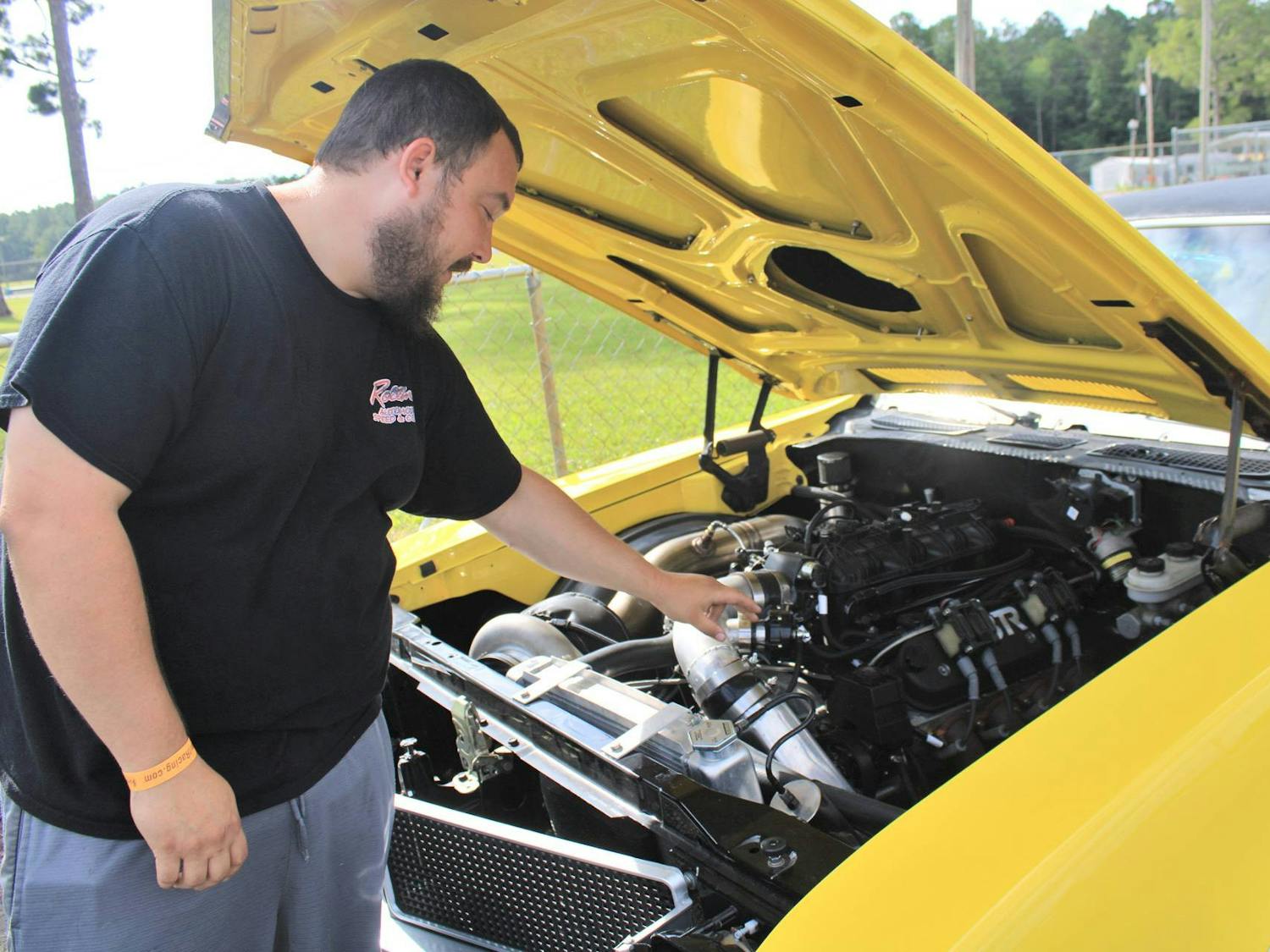 Michael Fair, 31, explains the engine of his Buick Skylark at the Gainesville Raceway on Saturday, July 15, 2023. 