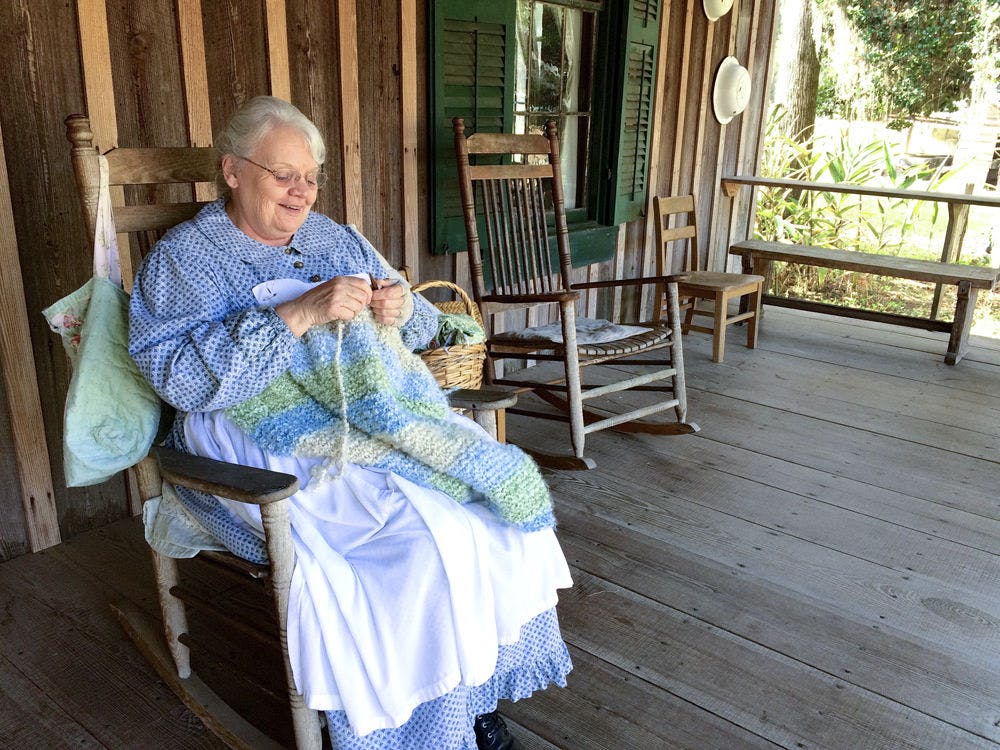 <p class="p1">Dorothy James, a 69-year-old volunteer at Dudley Farm Historic State Park, knits on the front porch Saturday at the park’s 25th annual Cane Day.</p>