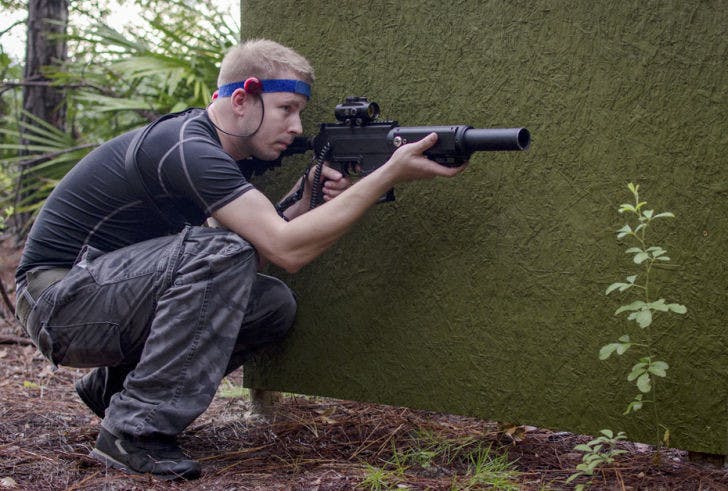 Rich Hibner crouches behind an obstacle at the new M2 Battlesports field in Newberry on Saturday.