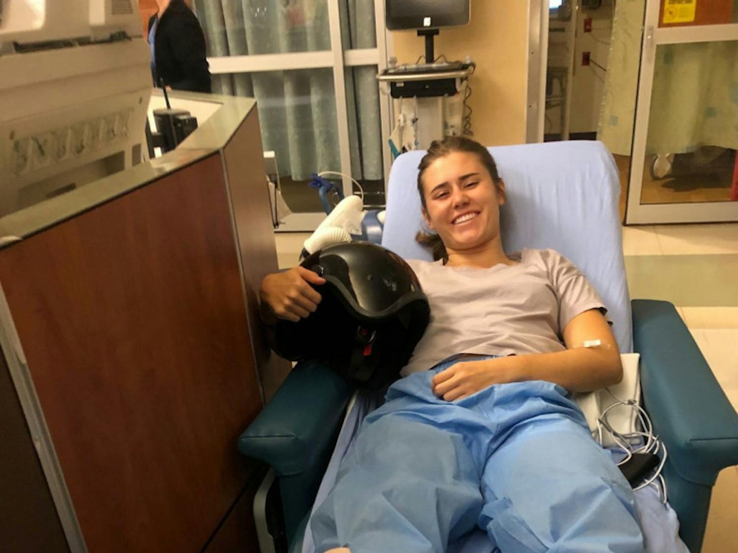 Mia Acker holding her scooter helmet in UF Health Shands Emergency Room hours after her scooter accident on West University Avenue.&nbsp;