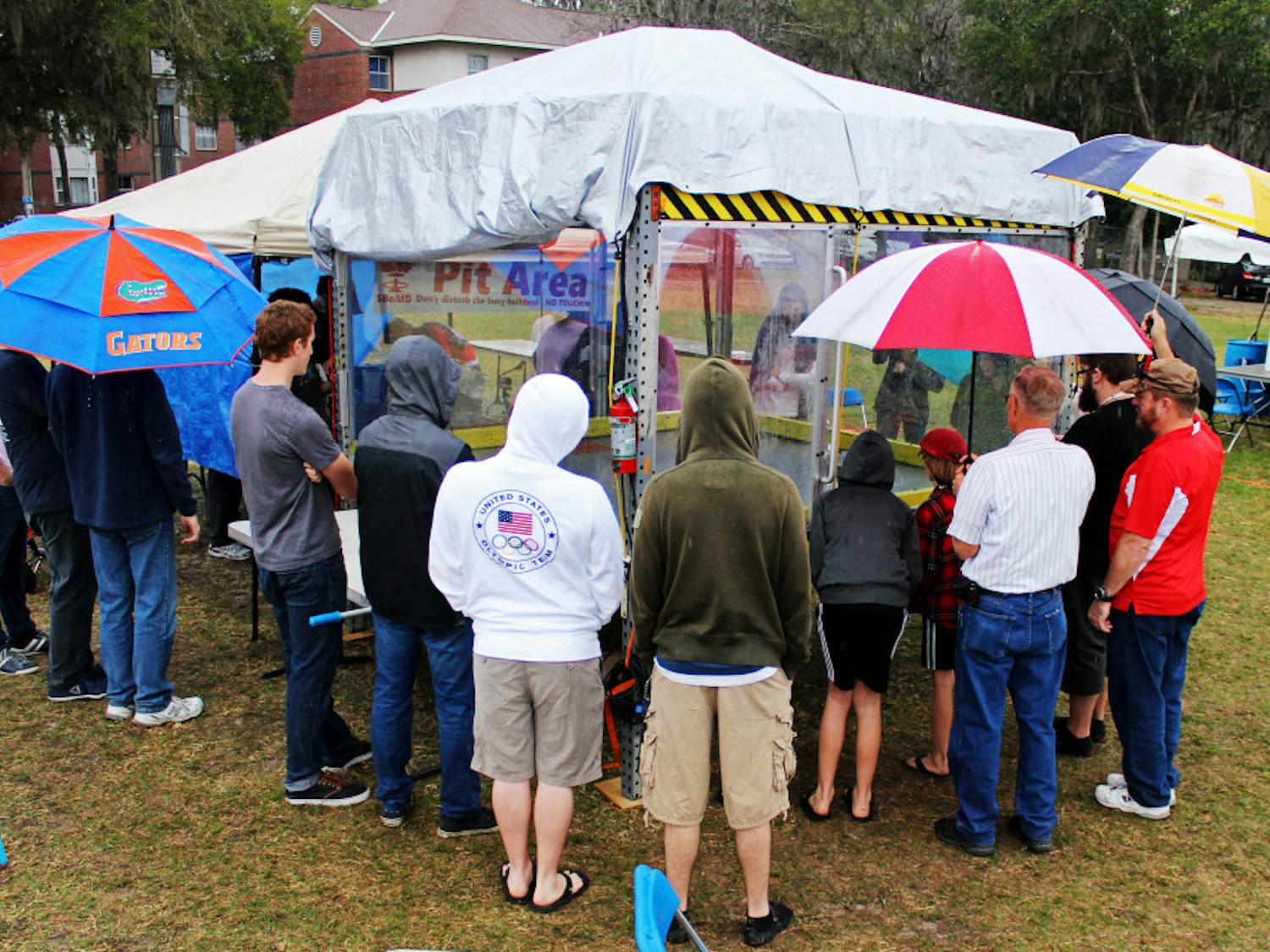 Attendees of the Engineering Festival crowd around a display area in the rain on Saturday. The group watched robots go head to head in what some called "combat robotics."