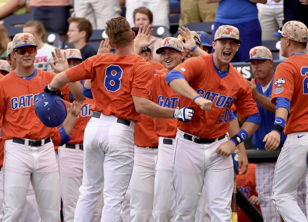 Florida's Harrison Bader (8) celebrates his solo home run against Miami with teammates at the dugout, in the first inning of an NCAA College World Series baseball elimination game at TD Ameritrade Park in Omaha, Neb., Wednesday, June 17, 2015.