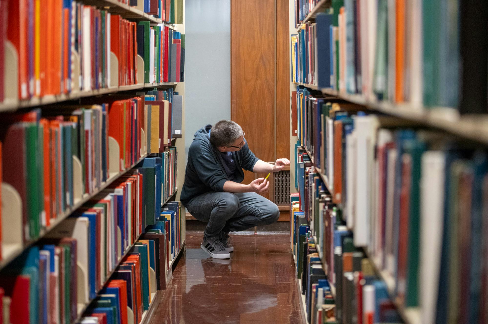 Fine Arts Library employee searches for a book on the shelves on Sept. 15th, 2025.