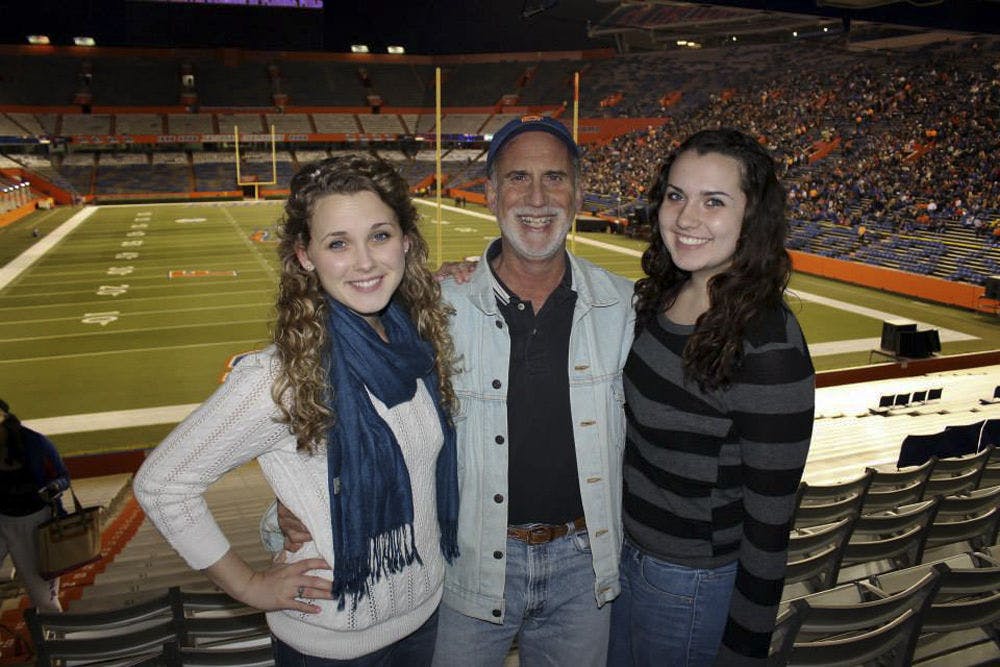 <p>Karl Kaufmann poses with his daughters Kelli, left, 20, and Kaitlyn, 16, in Ben Hill Griffin Stadium during Gator Growl on Nov. 9, 2013. The 59-year-old has been the announcer for Gator Growl since 1980.</p>