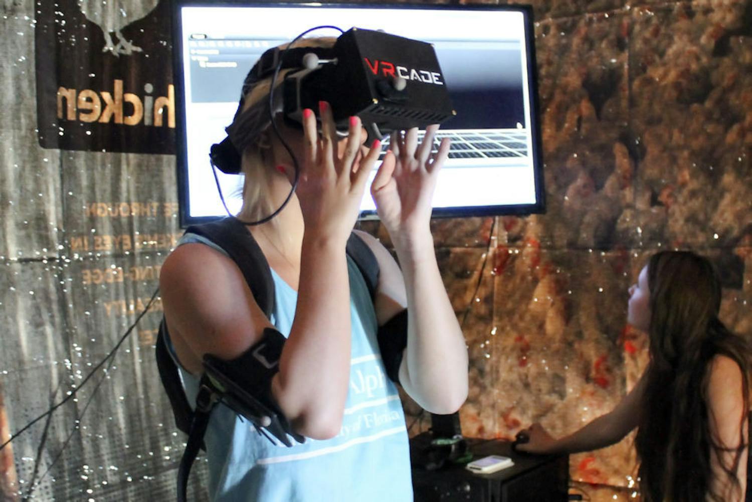 Kaley Thomas, a 21-year-old UF journalism junior, dons a virtual reality headset Monday afternoon to experience PETA2’s “I, Chicken,” a virtual reality experience in which participants become a chicken that is captured by a farmer.