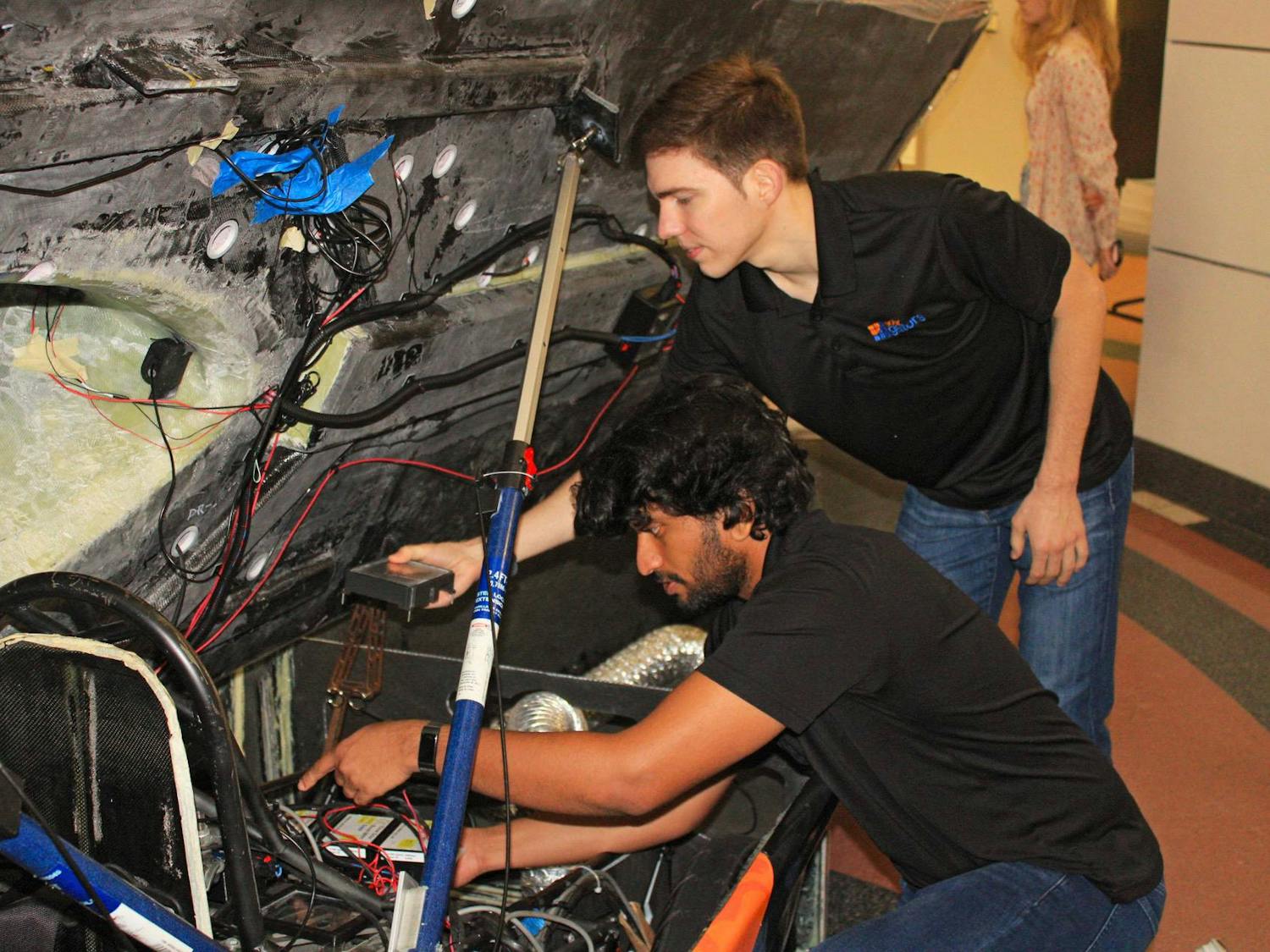 Yashasvi Bhat (left) and Taylor Gerke (right) adjust the wiring of the Sunrider at UF&#x27;s New Engineering Building on Thursday, June 22, 2023.