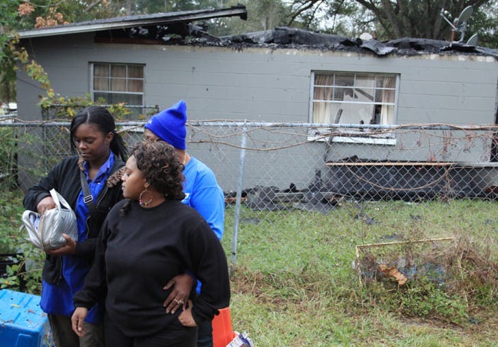 Shamon Williams (LEFT) holds a Bible with her sister Keambrea Smith (CENTER) and family friend Teresa White (BACK) after their house of 11 years caught fire on Friday, Nov. 16. The Bible is one of the only things that escaped from the area affected by the fire that occurred at 1420 SE 41st Place. The Rev. Olivia Campbell Parler will be arranging a fundraising event to help cover the family’s needs. For more information, contact Parler at 352-575-5541.