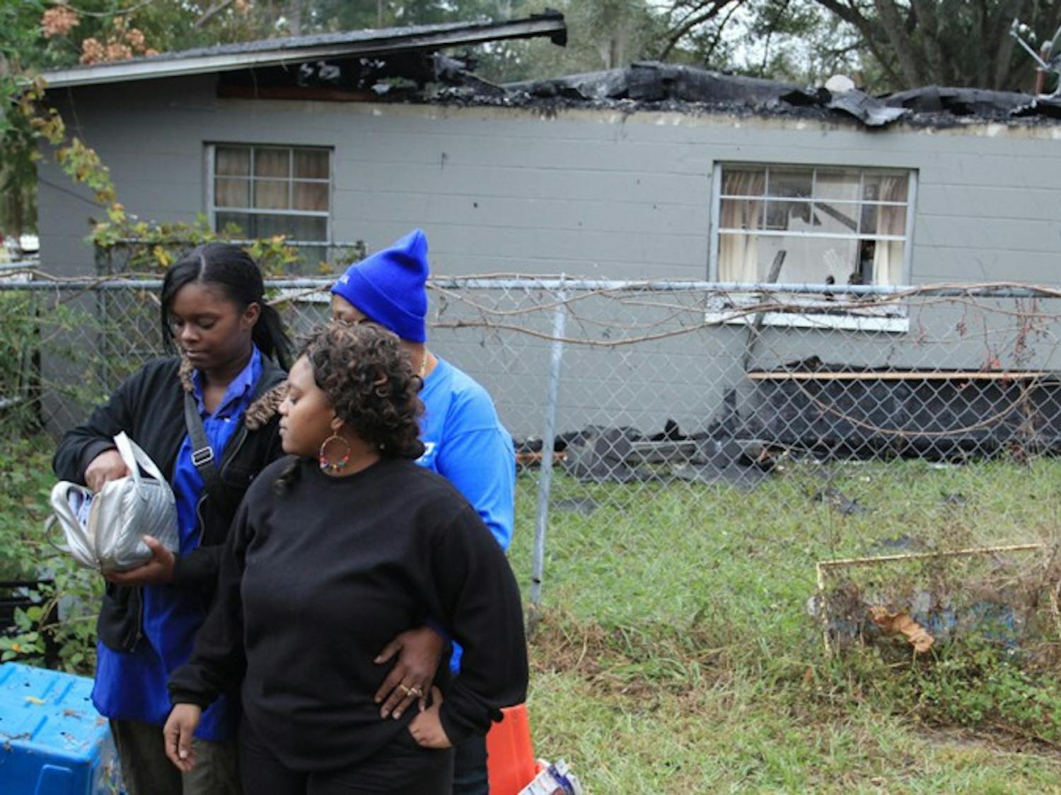 Shamon Williams (LEFT) holds a Bible with her sister Keambrea Smith (CENTER) and family friend Teresa White (BACK) after their house of 11 years caught fire on Friday, Nov. 16. The Bible is one of the only things that escaped from the area affected by the fire that occurred at 1420 SE 41st Place. The Rev. Olivia Campbell Parler will be arranging a fundraising event to help cover the family’s needs. For more information, contact Parler at 352-575-5541.