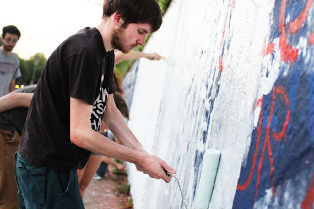 <p>Josh Bush, a 21-year-old UF computer science student, paints on the 34th Street Wall as part of a UF SDS event Monday evening.</p>