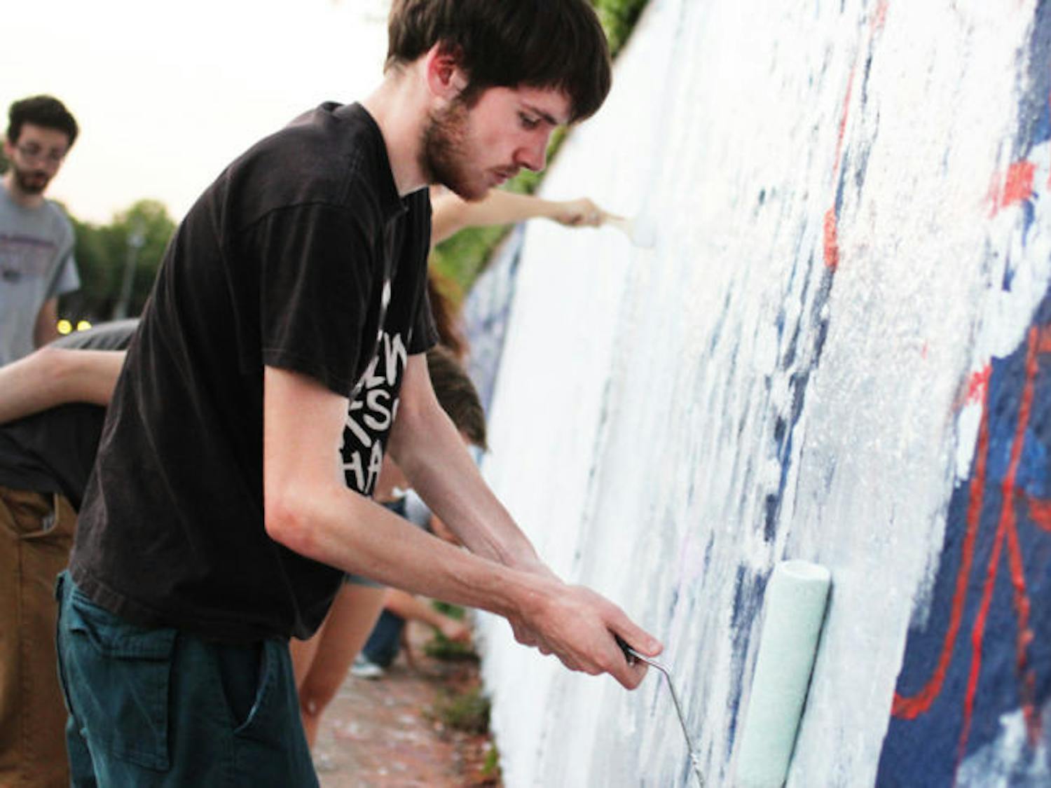 Josh Bush, a 21-year-old UF computer science student, paints on the 34th Street Wall as part of a UF SDS event Monday evening.