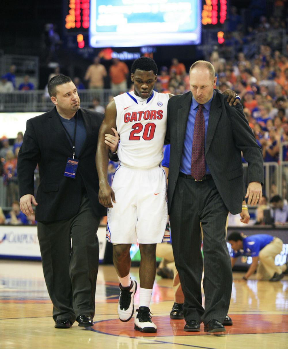 <p align="justify">Trainers help Michael Frazier II (20) off the court after the freshman guard suffered a concussion in UF’s win against Arkansas on Saturday.</p>