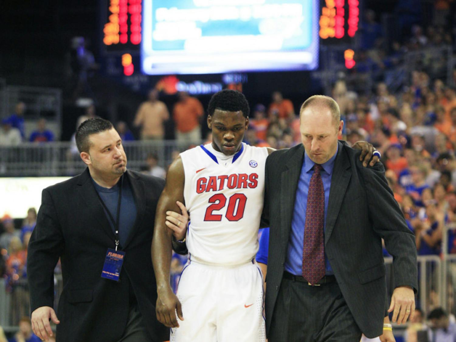 Trainers help Michael Frazier II (20) off the court after the freshman guard suffered a concussion in UF’s win against Arkansas on Saturday.