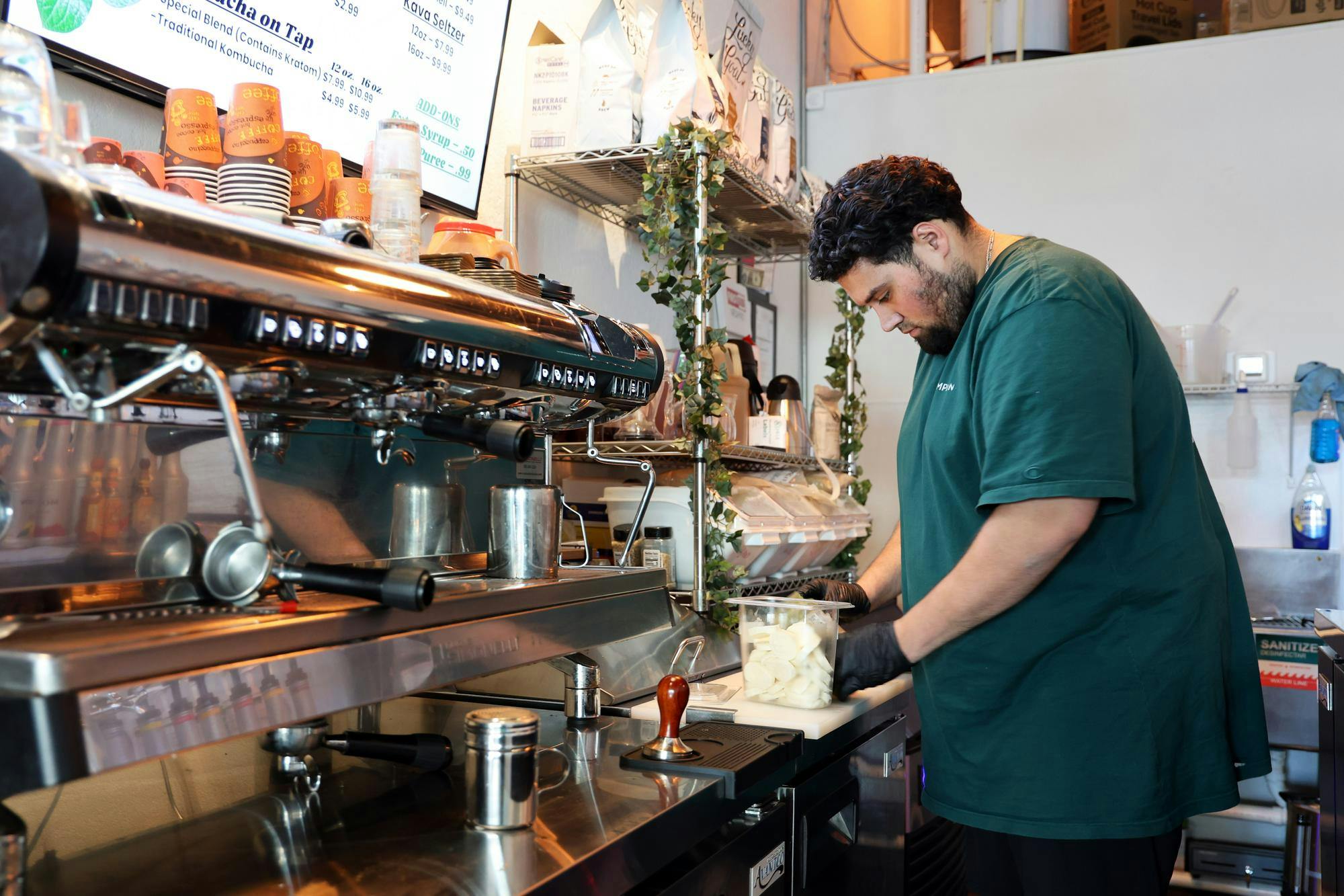 Brew&amp;Root owner Bekir “Beck” Mansi prepares a sandwich for a pickup order inside the shop in Gainesville, Fla., on Friday, Feb. 13, 2026.