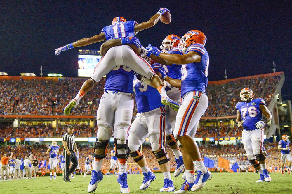 <p>Demarcus Robinson (11) leaps into Roderick Johnson (55) to celebrate his TD catch in the third quarter of the Gators and Wildcats matchup in Ben Hill Griffin Stadium during UF's 36-30 triple overtime win on Sept. 13, 2014.</p>
