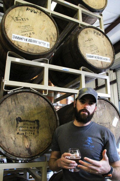 Luke Kemper, 30, enjoys a cold beer while he explains the brewing process Friday afternoon at Swamp Head Brewery, 3140 SW 42nd Way.