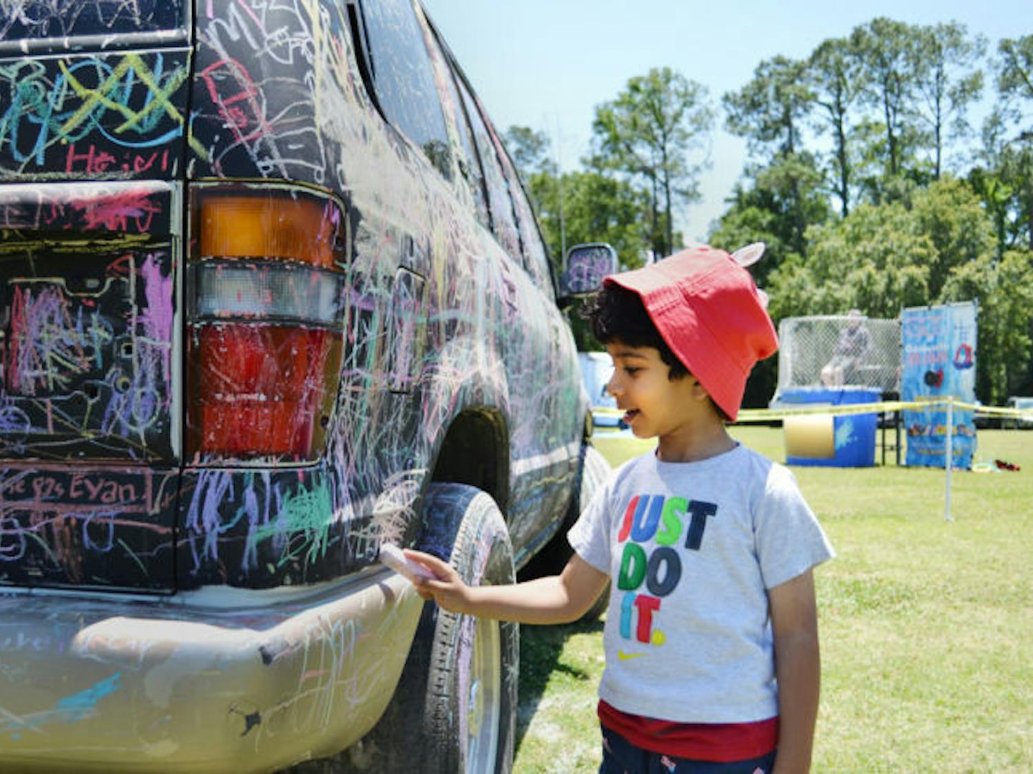 Majeed Aljabhan, 3, smiles as he draws a heart on a SUV painted like a chalkboard at the Sweet Dreams’ Touch-a-Truck event Saturday afternoon. The event provided hands-on play on trucks for children and adults.