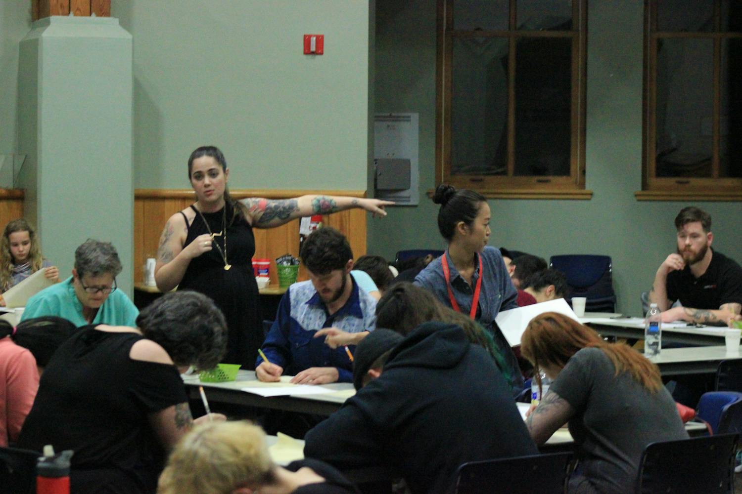Standing to the left, Kristyn "Bat" Lopez, a tattooist for Death or Glory Tattoo, directs her Thursday night flash-tattoo workshop class at Alachua County Public Library's Headquarters Branch to drawing supplies.