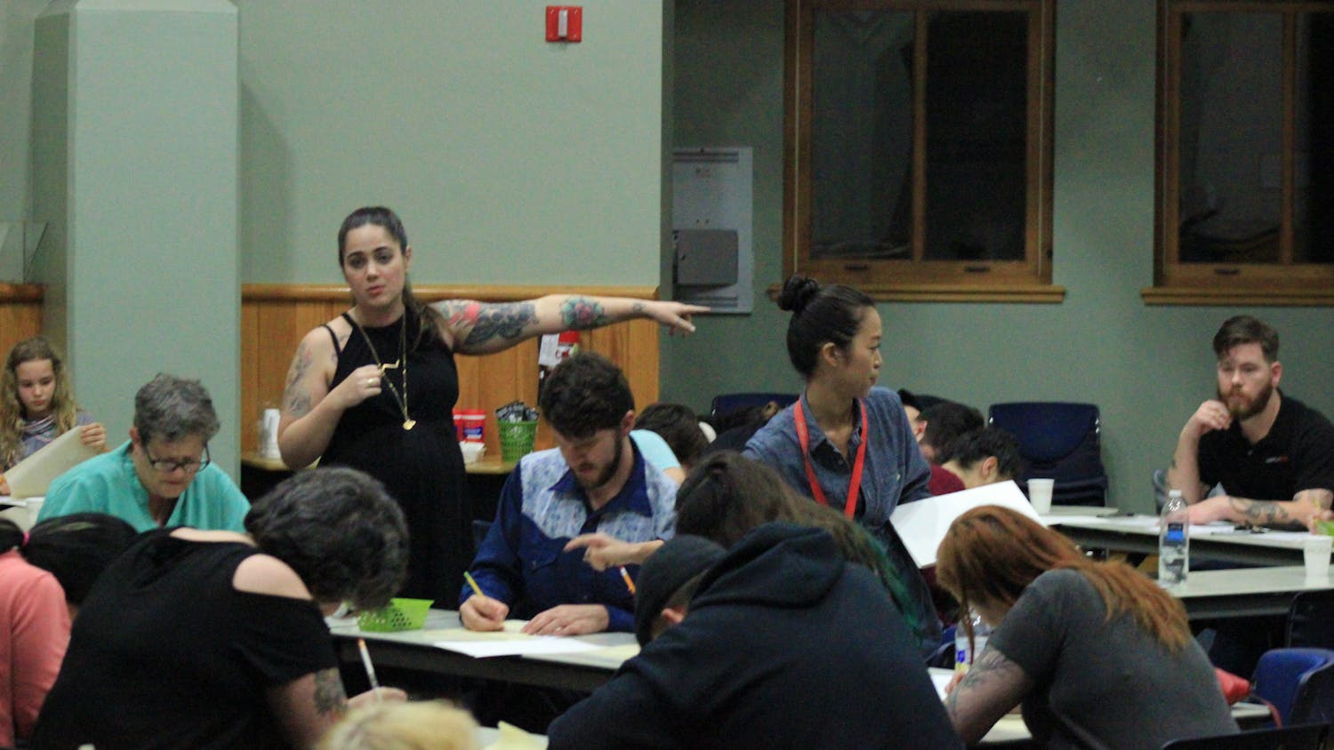 Standing to the left, Kristyn "Bat" Lopez, a tattooist for Death or Glory Tattoo, directs her Thursday night flash-tattoo workshop class at Alachua County Public Library's Headquarters Branch to drawing supplies.