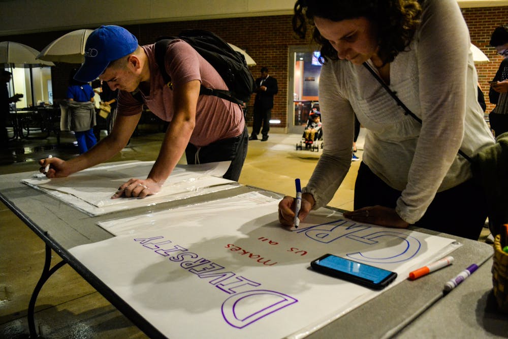 <p>Edward Zambrano, a 22-year-old UF political science senior, and Grace Burmester, a 30-year-old faculty member from the School of Forest Resources and Conservation, create signs for the Martin Luther King Jr. Celebration March and Kickoff.</p>