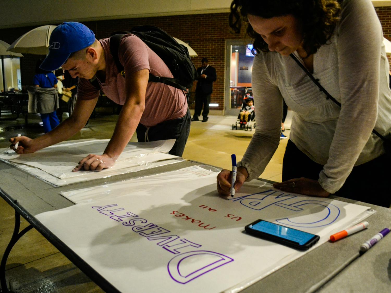 Edward Zambrano, a 22-year-old UF political science senior, and Grace Burmester, a 30-year-old faculty member from the School of Forest Resources and Conservation, create signs for the Martin Luther King Jr. Celebration March and Kickoff.
