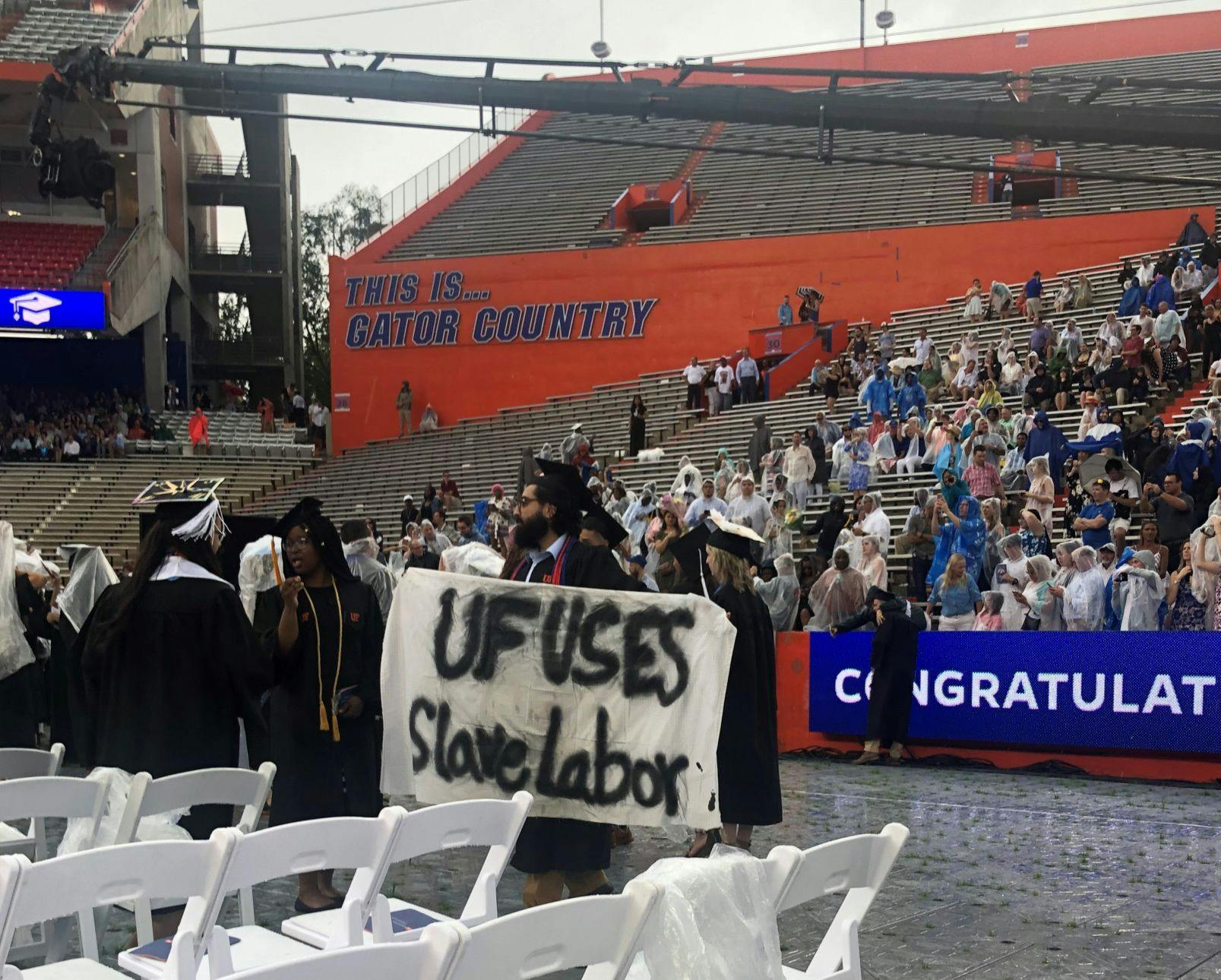 Syed Muhammad Omar holds a banner during the College of Liberal Arts and Sciences commencement ceremony on Sunday.&nbsp;Omar, a 27-year-old UF psychology bachelor’s graduate, said he is involved with Divest UF.