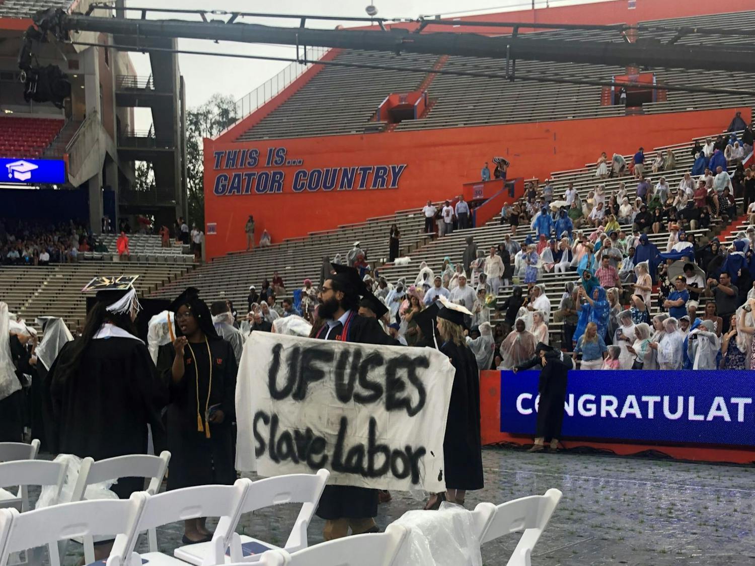 Syed Muhammad Omar holds a banner during the College of Liberal Arts and Sciences commencement ceremony on Sunday. Omar, a 27-year-old UF psychology bachelor’s graduate, said he is involved with Divest UF.