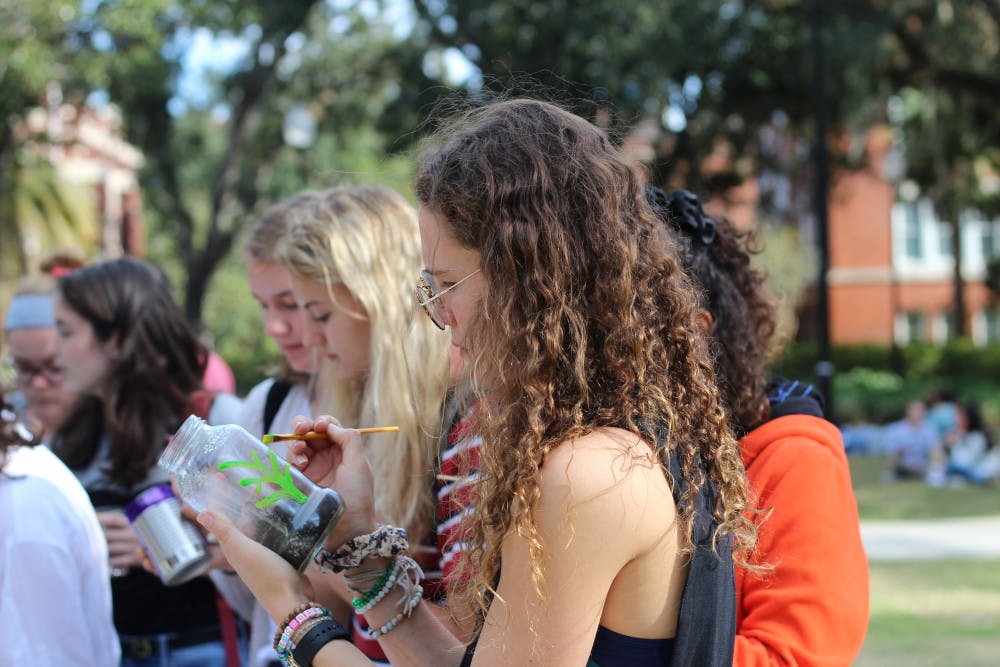 Leanne Shaffer decorates her recycled glass jar at Plantsgiving before planting beans and bell peppers. 