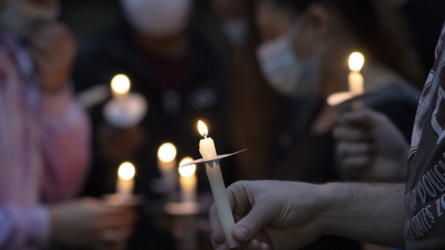 Alrededor de 80 personas sostienen velas y se reúnen durante una vigilia el domingo 14 de febrero del 2021 por los asesinados en el tiroteo en la escuela secundaria Marjory Stoneman Douglas hace tres años.  