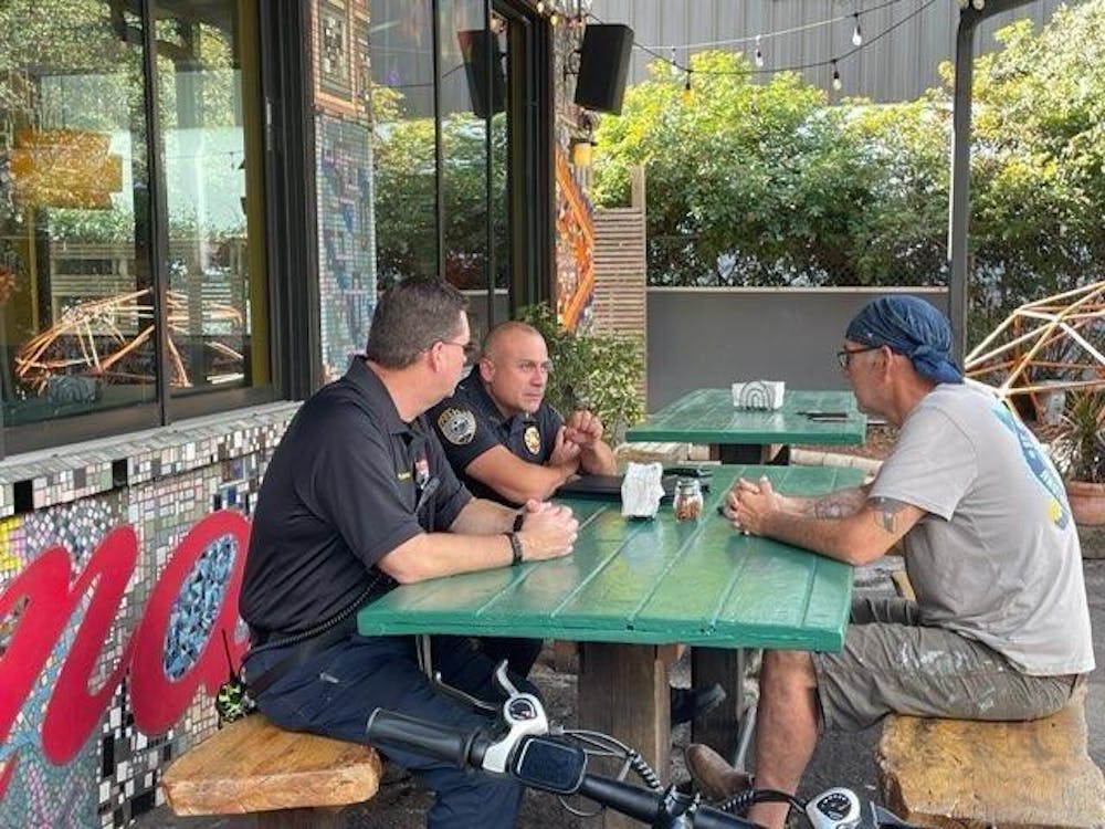 Satchel Raye, the owner of Satchel's Pizza, speaks to officials from Gainesville Police Department and Gainesville Fire Rescue after the arson of the Satchel's Pizza van. (Photo courtesy of Satchel Raye) 