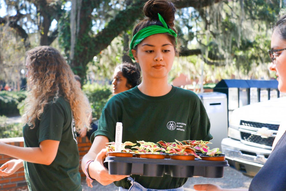 Mia Sewall, an 18-year-old UF communication sciences and disorders freshman, helps unload plants from two delivery trucks for the UF College Plant Initiative's Plant Drop Friday morning. One thousand plants were given away to students in Turlington Plaza.