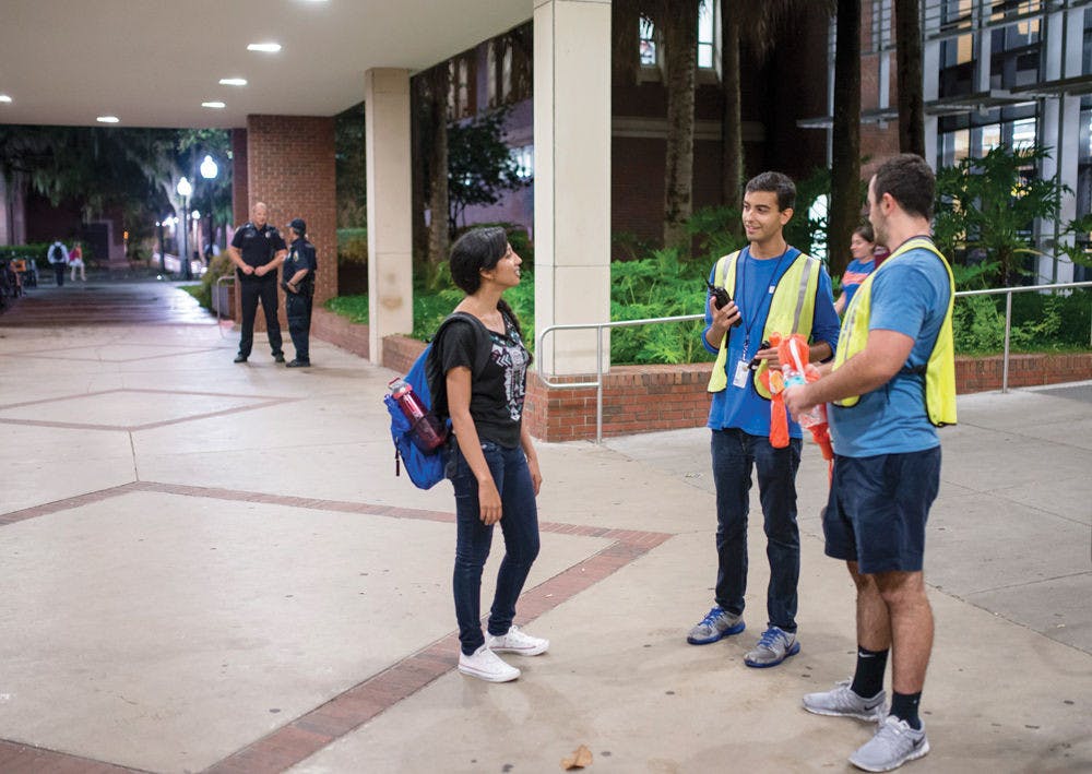 <p class="p1">From left, UF nutritional sciences freshman Stephie Cyril, 17, requests a walking escort from student volunteers, UF political science junior Ryan Wolis, 20, and UF finance sophomore Nathaniel Reiff, 19, outside Library West on Tuesday night.</p>