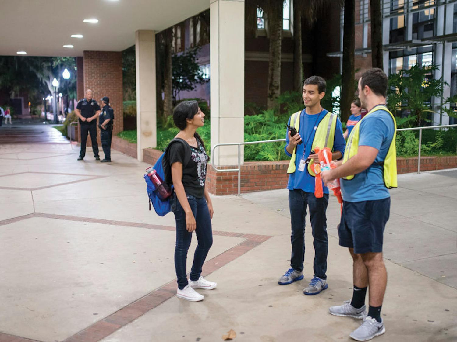 From left, UF nutritional sciences freshman Stephie Cyril, 17, requests a walking escort from student volunteers, UF political science junior Ryan Wolis, 20, and UF finance sophomore Nathaniel Reiff, 19, outside Library West on Tuesday night.