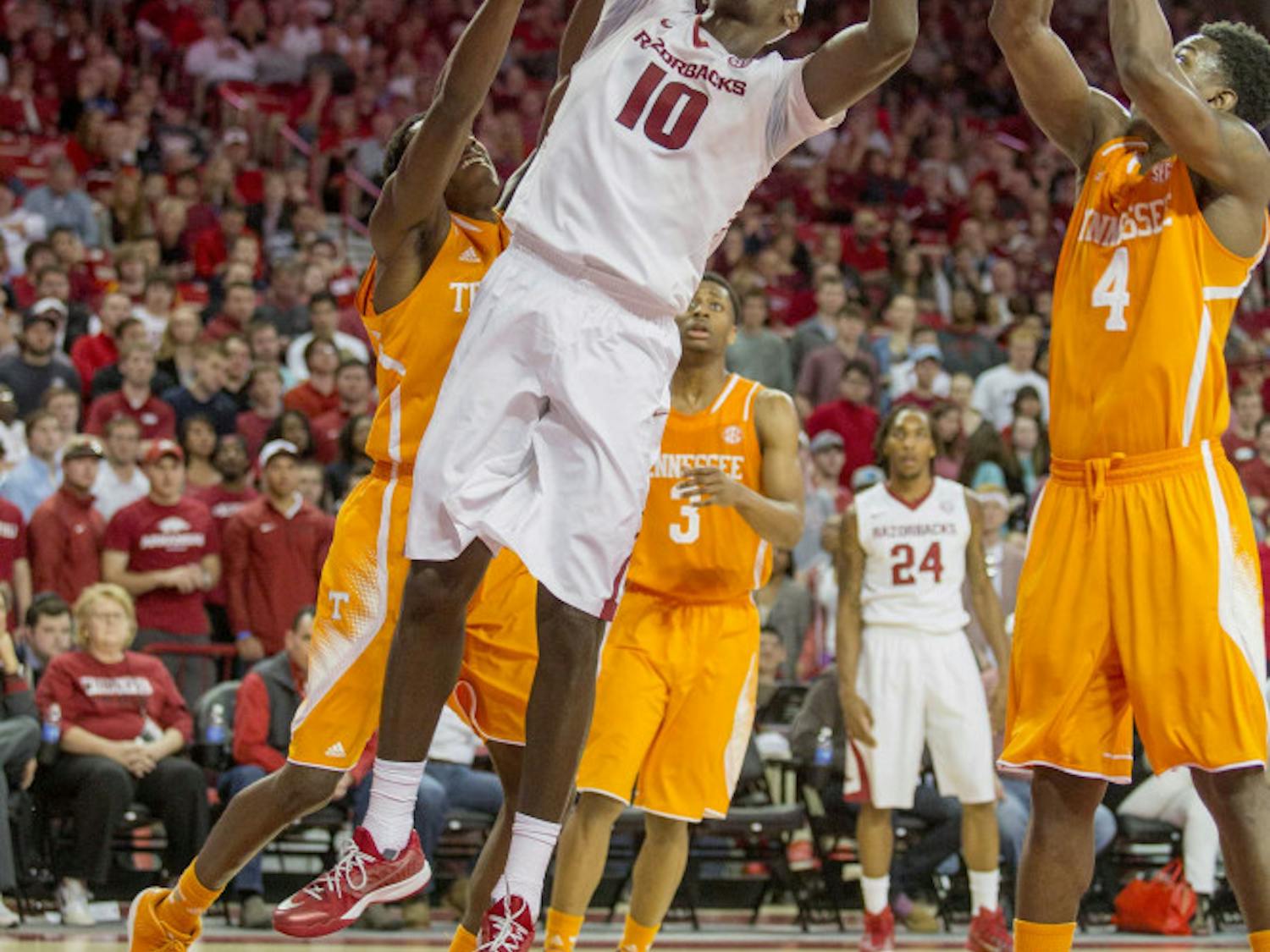 Arkansas forward Bobby Portis, center, shoots a layup as Tennessee forward Armani Moore, right, guards during the second half of an NCAA college basketball game on Tuesday, Jan. 27, 2015, in Fayetteville, Ark. Arkansas defeated Tennessee 69-64.