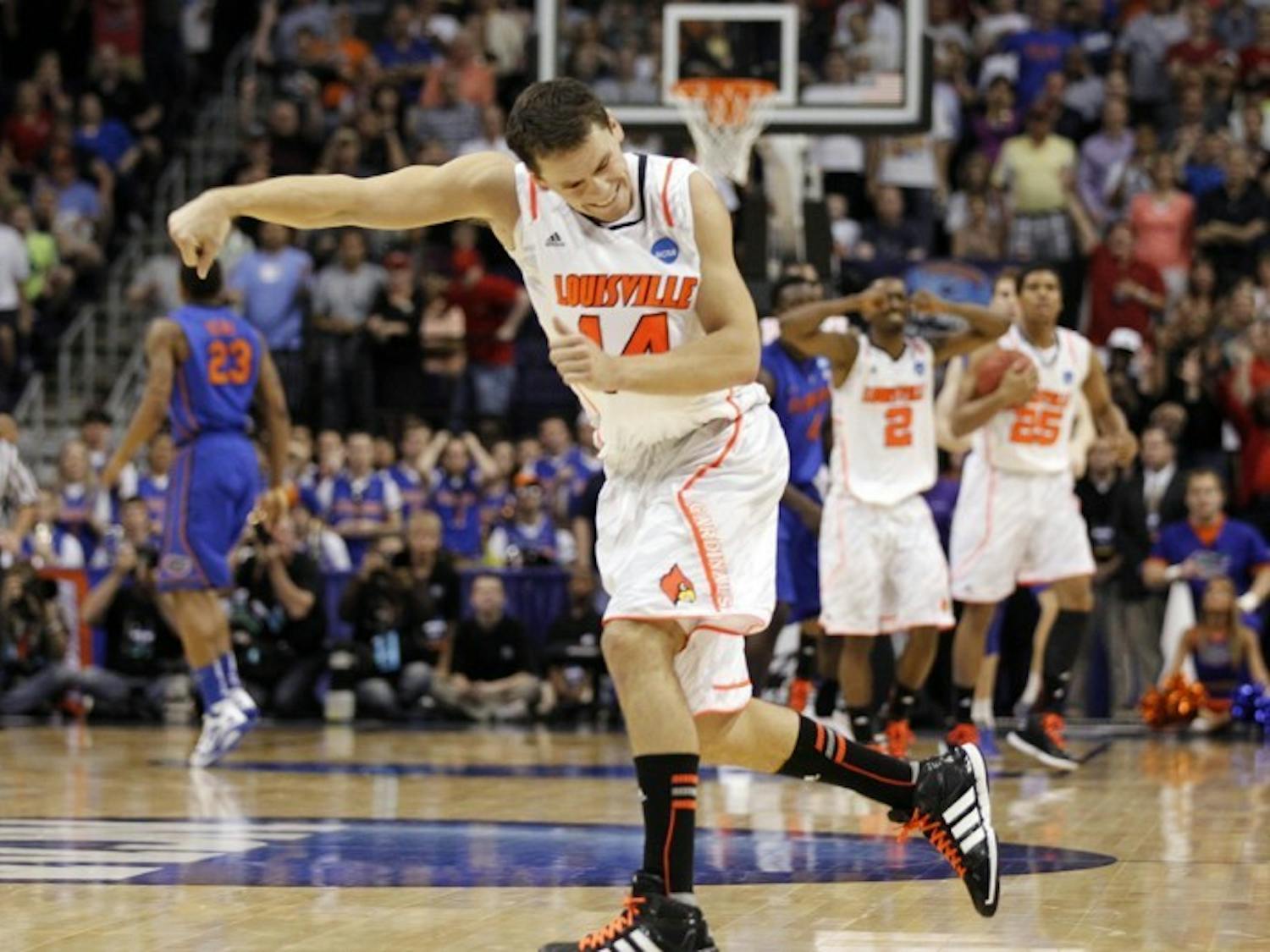 Louisville’s Kyle Kuric punches the air in celebration after the Cardinals overcame an 11-point deficit in the final nine minutes to hand the Gators their second consecutive Elite Eight loss.